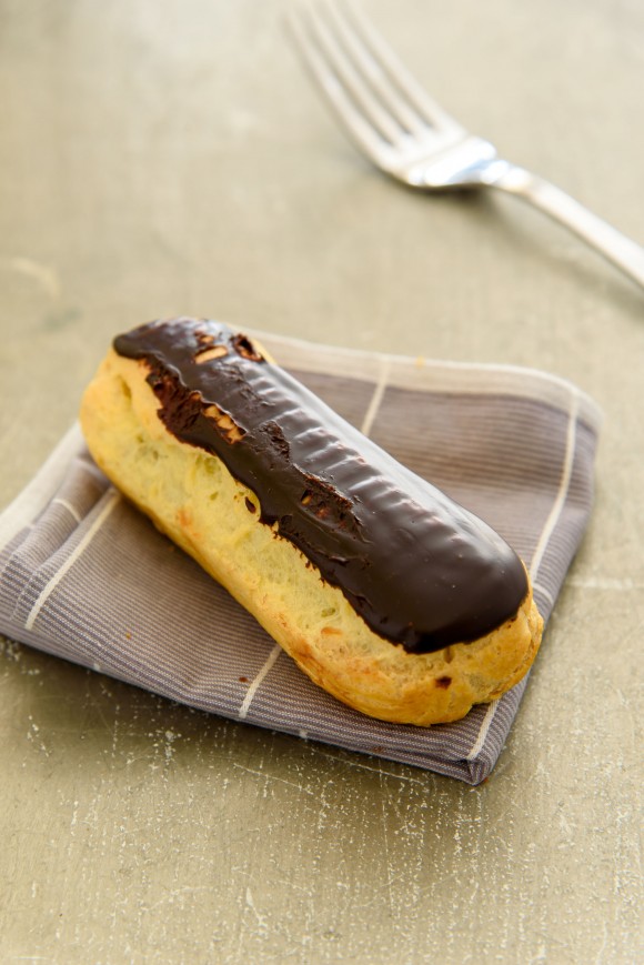 Selective focus on chocolate eclair on the napkin fold on the grunge table.